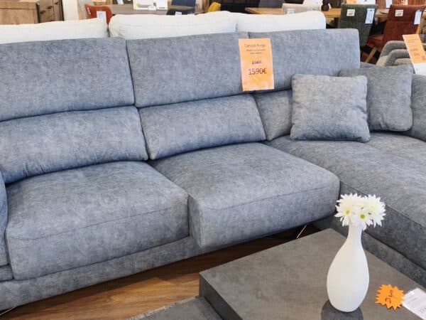 Blue sectional sofa with three back cushions and two throw pillows in a showroom, price tag visible on the center cushion.